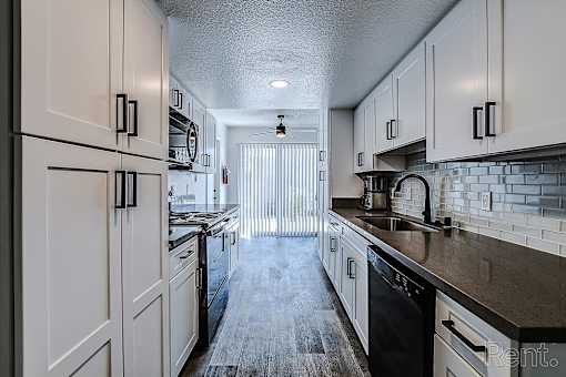 A kitchen with white cabinets and black appliances.