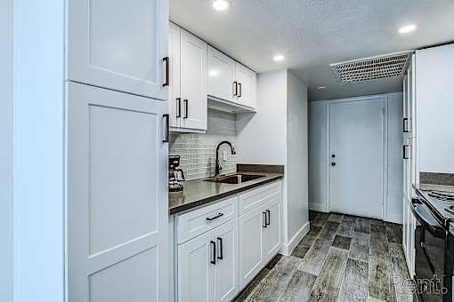 A kitchen with white cabinets and a wooden floor.