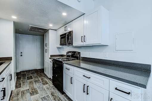 A kitchen with white cabinets and a black stove top.