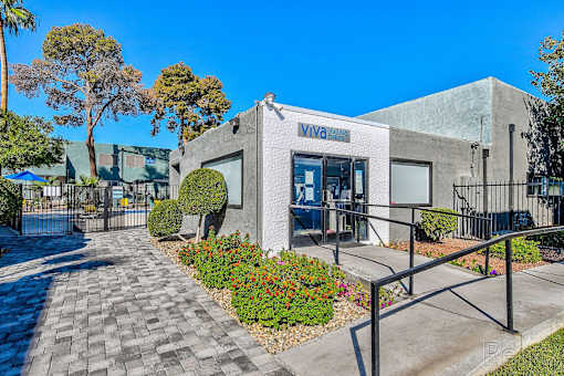 A building with the word "VIVA" on it is surrounded by a gate and has a walkway leading to the entrance.