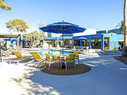 A blue umbrella is in the middle of a table and chairs.