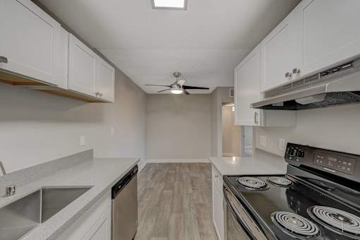 A modern kitchen with a stove, sink, and cabinets.