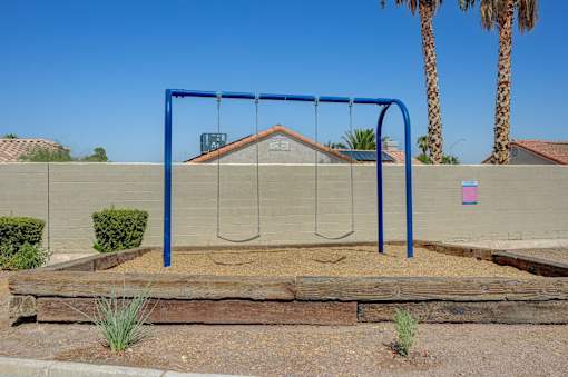 A playground swing set with a blue frame and a brown wooden slide.