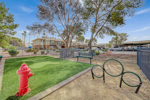 A red fire hydrant sits on a green lawn next to a playground.