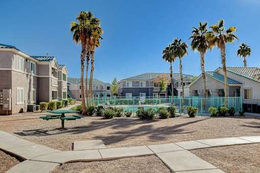 A sunny day at a residential area with palm trees and a green bench.