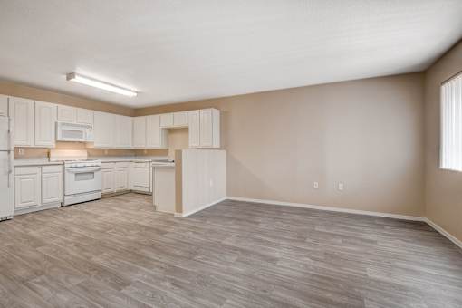 A kitchen with white cabinets and a wooden floor.