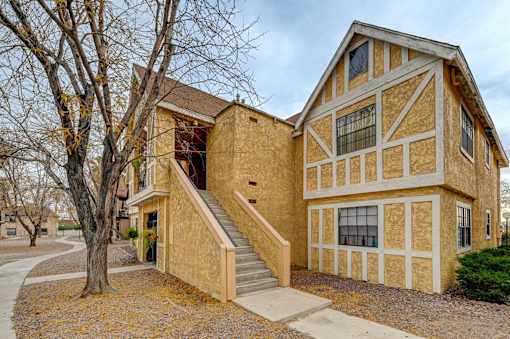 A house with a brown and tan exterior and a staircase leading to the front door.