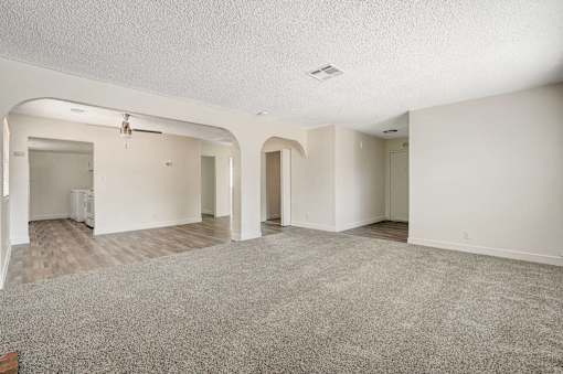 A spacious room with a carpeted floor and white walls.