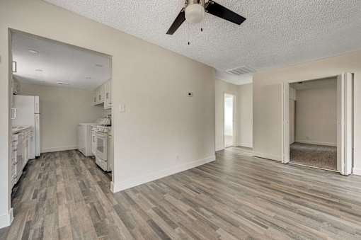 A room with a ceiling fan and wood flooring.