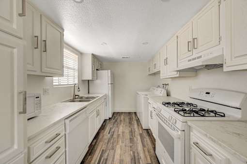 A kitchen with white appliances and cabinets.