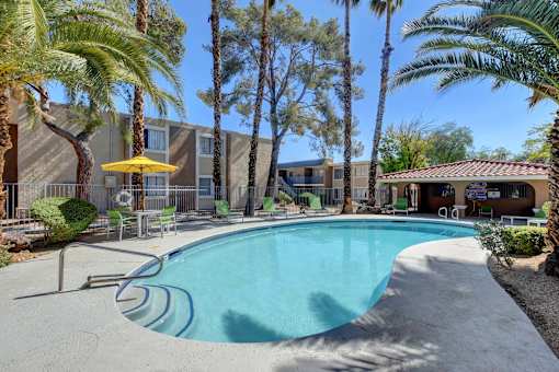 A pool surrounded by palm trees and a yellow umbrella.