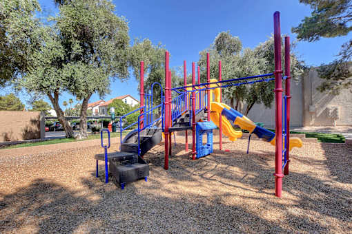 A playground with a yellow slide and red and blue climbing structure.