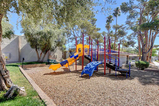 A playground with a yellow slide and a blue bench.