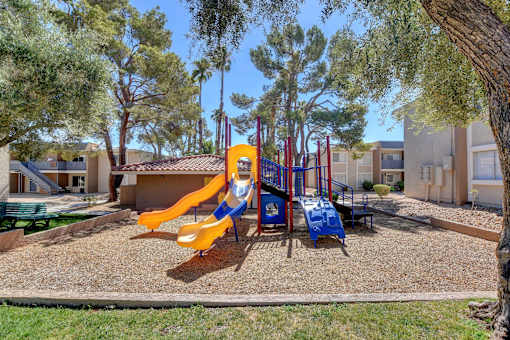 A playground with a yellow slide and a blue slide.