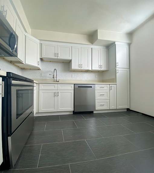 A kitchen with white cabinets and a black fridge.