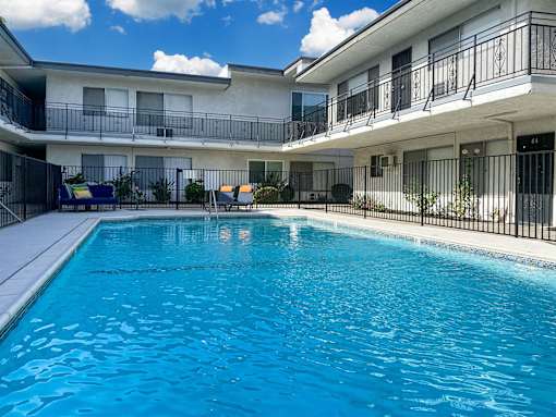 A swimming pool in front of a multi-story apartment building.