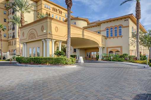 A large, beige building with palm trees in front.