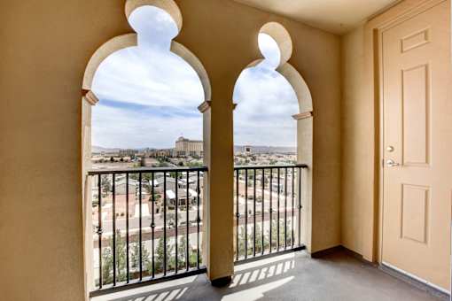 A balcony with a view of a cityscape through arched windows.