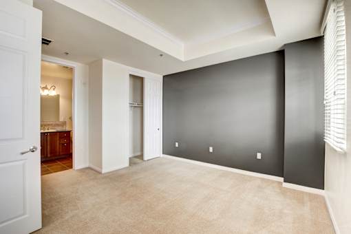 A large empty room with a doorway leading to a kitchen.