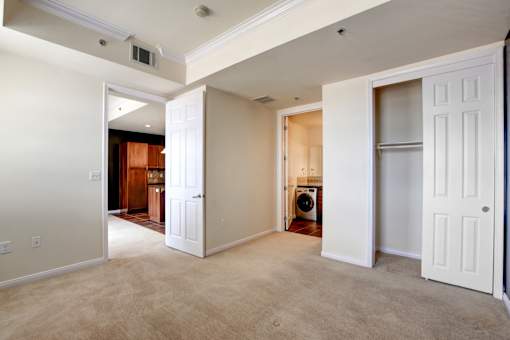A room with white walls and a carpeted floor with a washing machine in the corner.