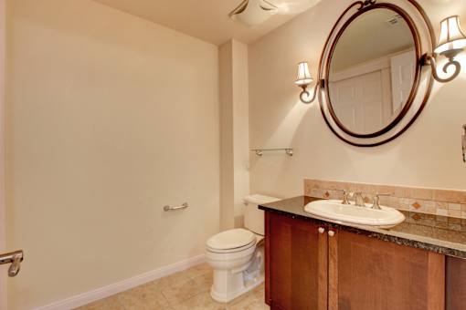 A bathroom with a toilet, sink, and mirror.