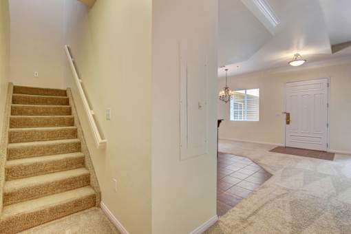 A hallway with a staircase and a rug on the floor.