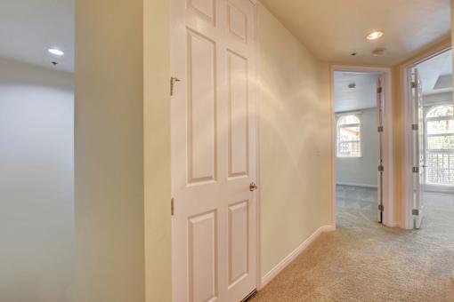 A white door is in a hallway with a tan carpet.