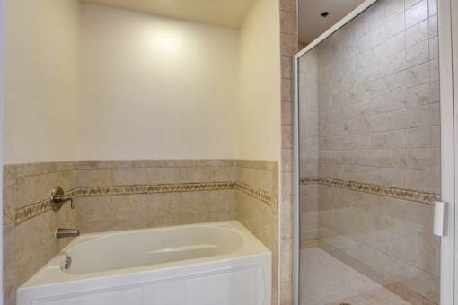 A white bathtub with a silver faucet is in a bathroom with tiled walls.