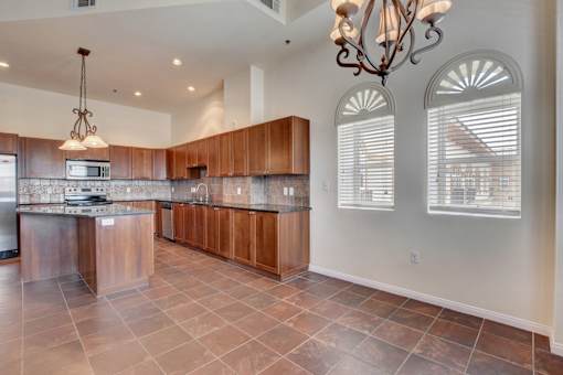 A kitchen with brown cabinets and a tile floor.