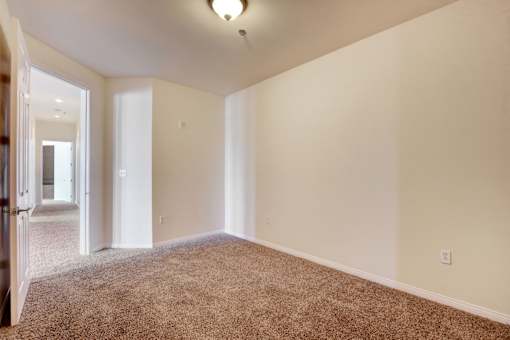 A large, empty room with carpeted flooring and white walls.