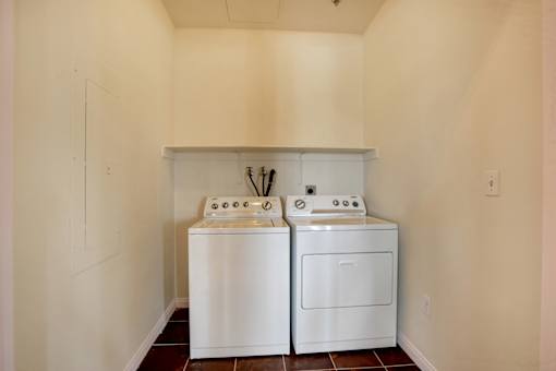 Two white front loading washing machines in a small laundry room.