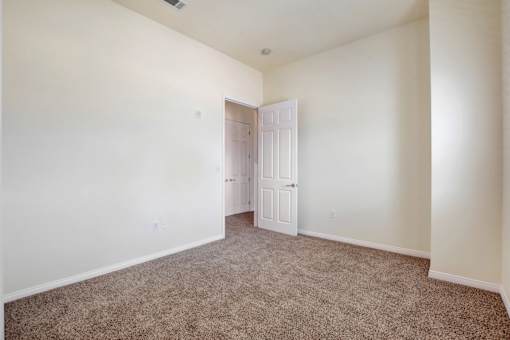 A room with a carpeted floor and a white door.