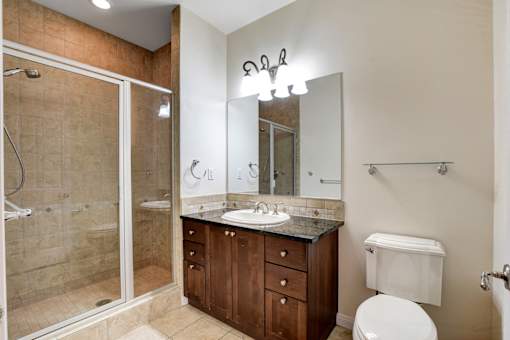 A bathroom with a walk-in shower, double sinks, and a toilet.