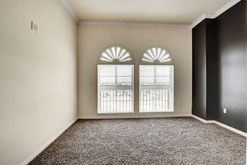 A room with a carpeted floor and a window with blinds.