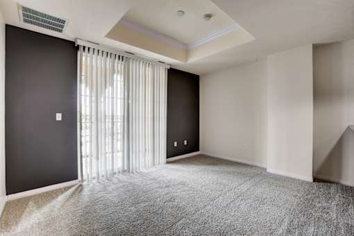 A room with a carpeted floor and a window with blinds.