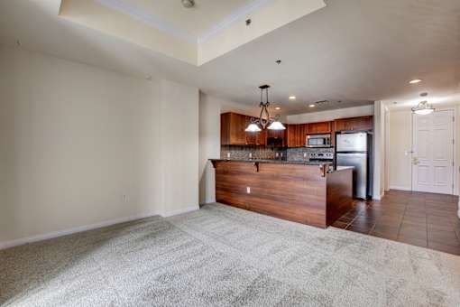 A spacious living room with a kitchen area in the background.