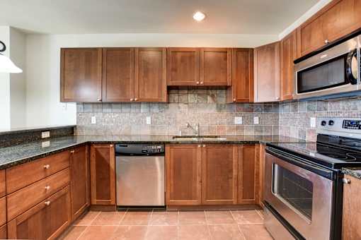 A kitchen with brown cabinets and black appliances.