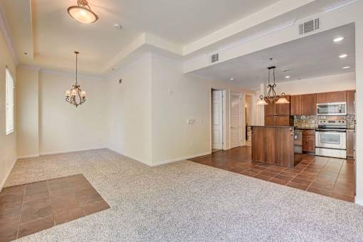 A spacious living room with a kitchen area in the background.