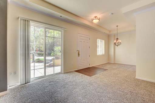 A room with a carpeted floor, a door, and a chandelier.