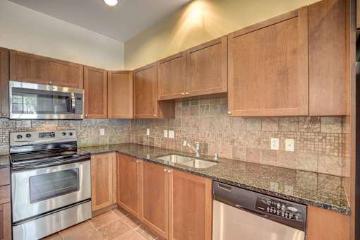 A kitchen with wooden cabinets and a granite countertop.
