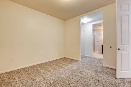 A room with a carpeted floor and a doorway leading to another room.