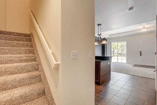 A staircase with a carpeted runner leads up to a white wall with a switch plate.