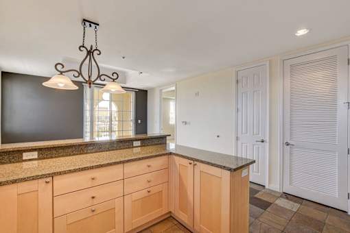 A kitchen with wooden cabinets and a hanging light fixture.