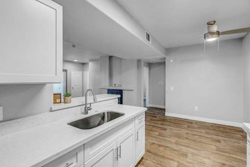 A modern kitchen with white cabinets and a wooden floor.