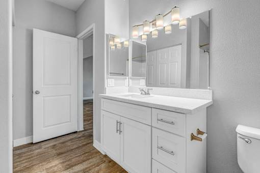 A white bathroom with a sink, mirror, and toilet.