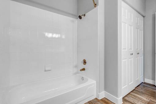 A white bathroom with a tub and a door.