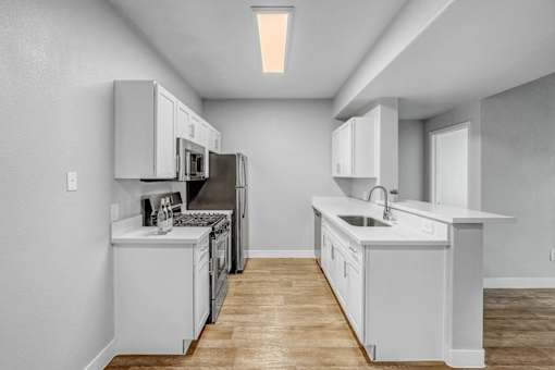 A modern kitchen with white cabinets and appliances.