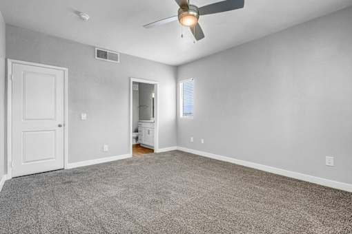 A room with a ceiling fan and carpeted floor.