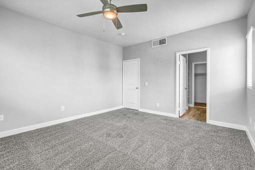 A room with a ceiling fan and carpeted floor.