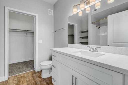 A white bathroom with a toilet, sink, and mirror.
